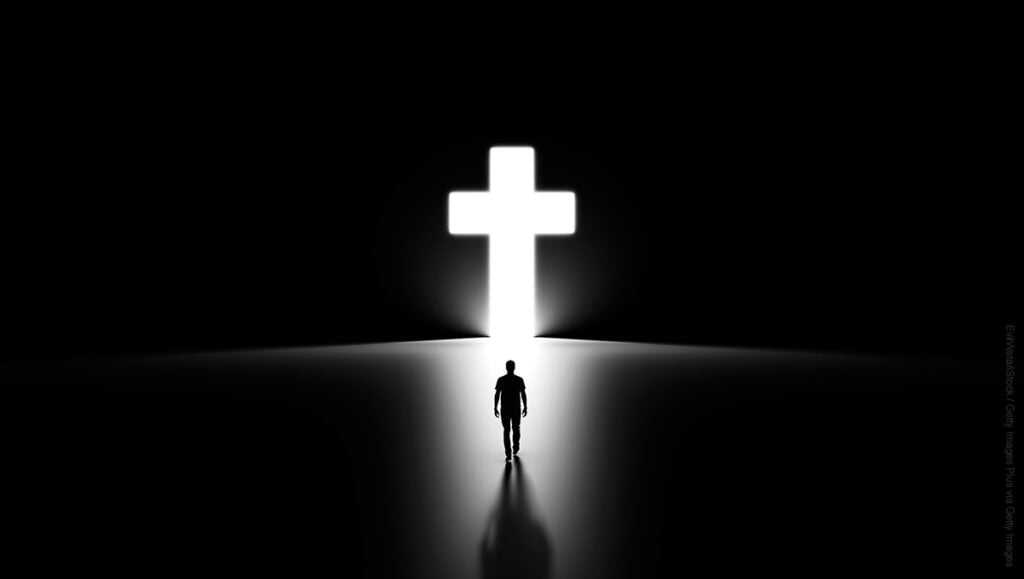 3D Silhouette of a Man Walking into Religious Cross Shaped Hole in the Wall Shinning Light Towards Him, Black Background.