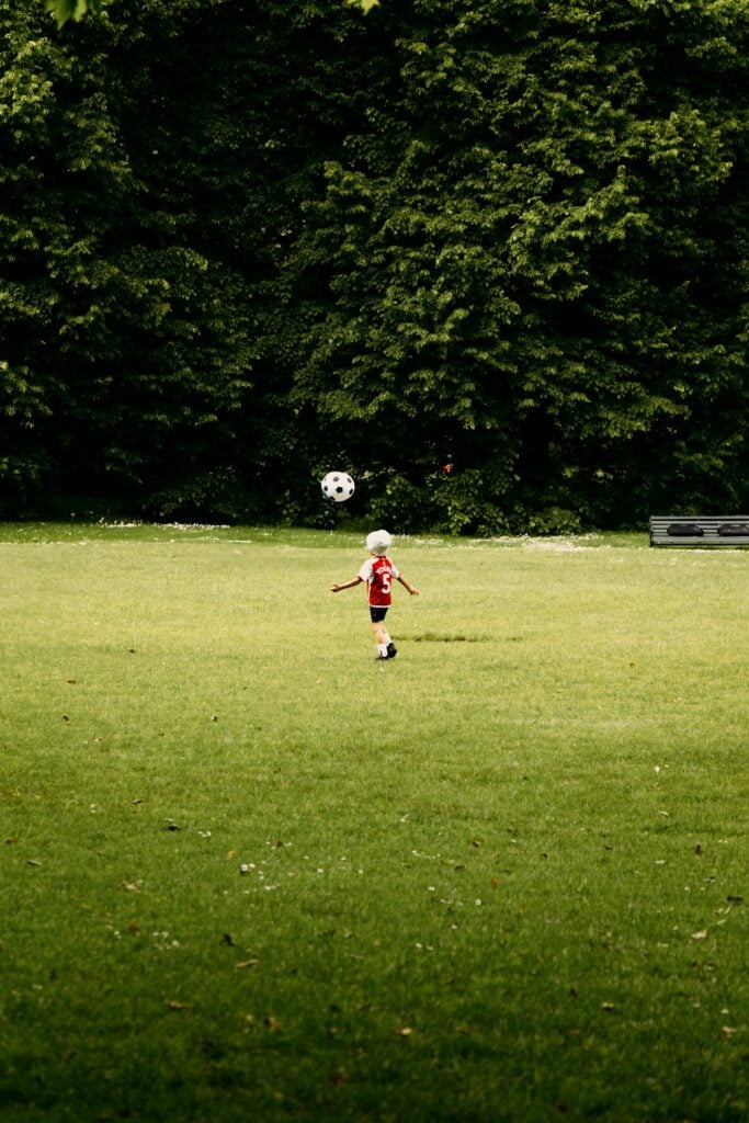 a young boy is playing soccer in a field
