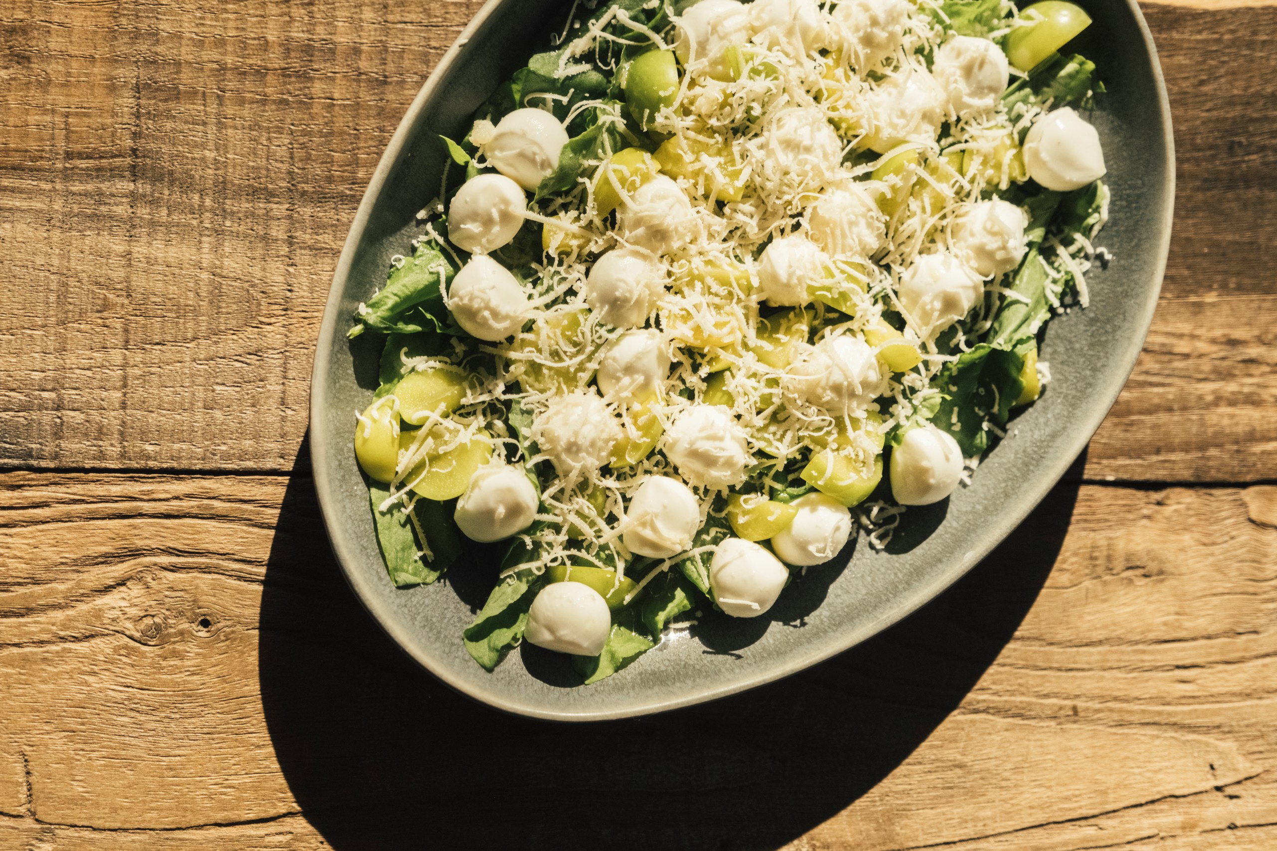 A large oval platter of salad with cheese and grapes.