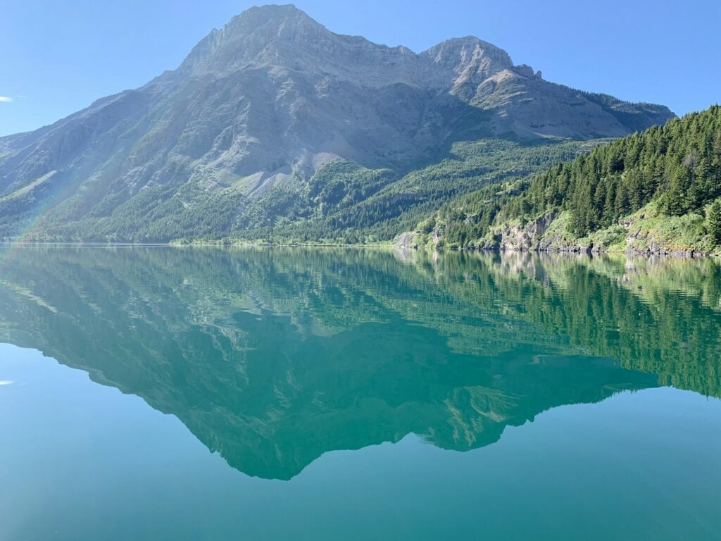 body of water viewing mountain under blue and white sky during daytime