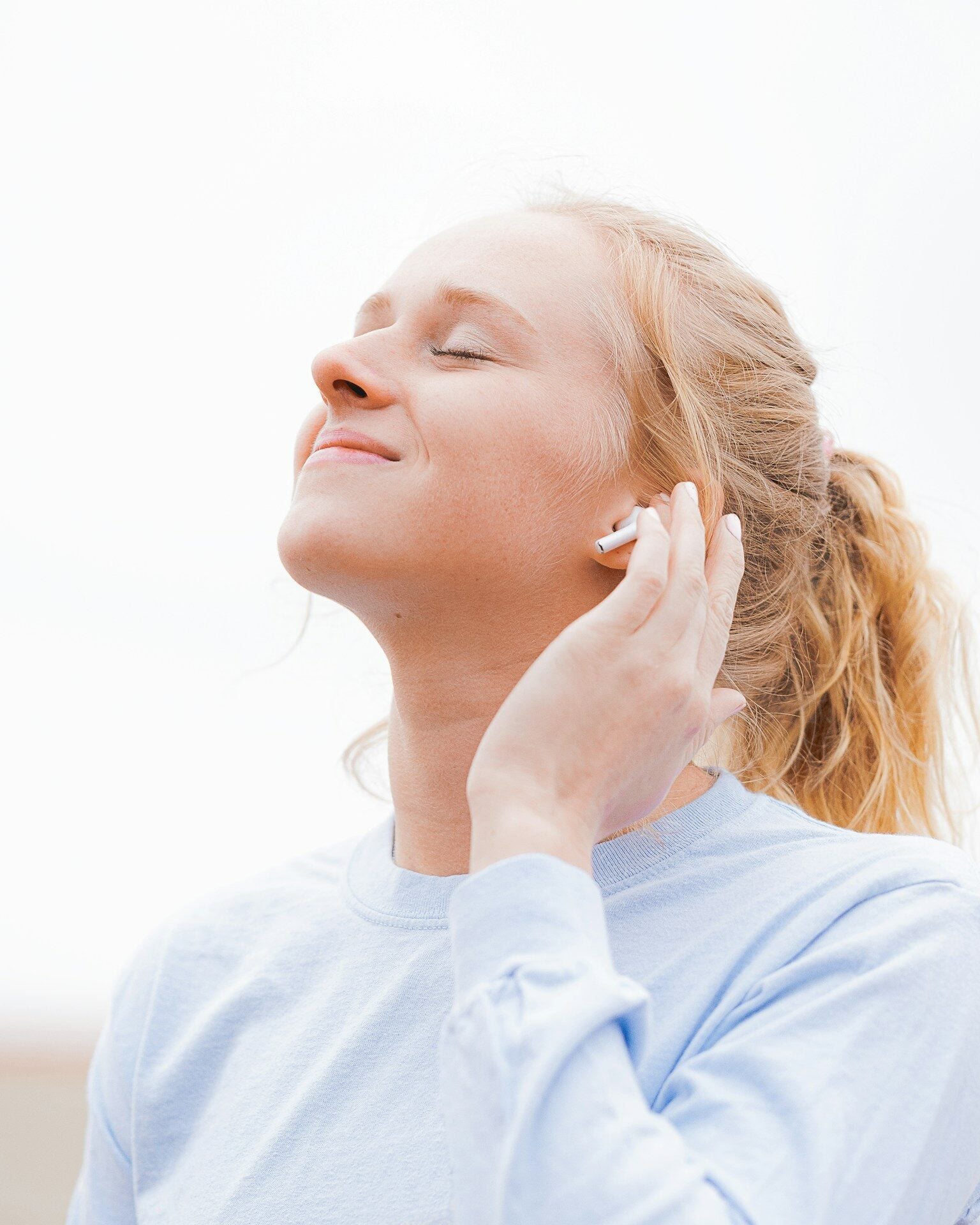 woman in white crew neck shirt covering her face with her hand