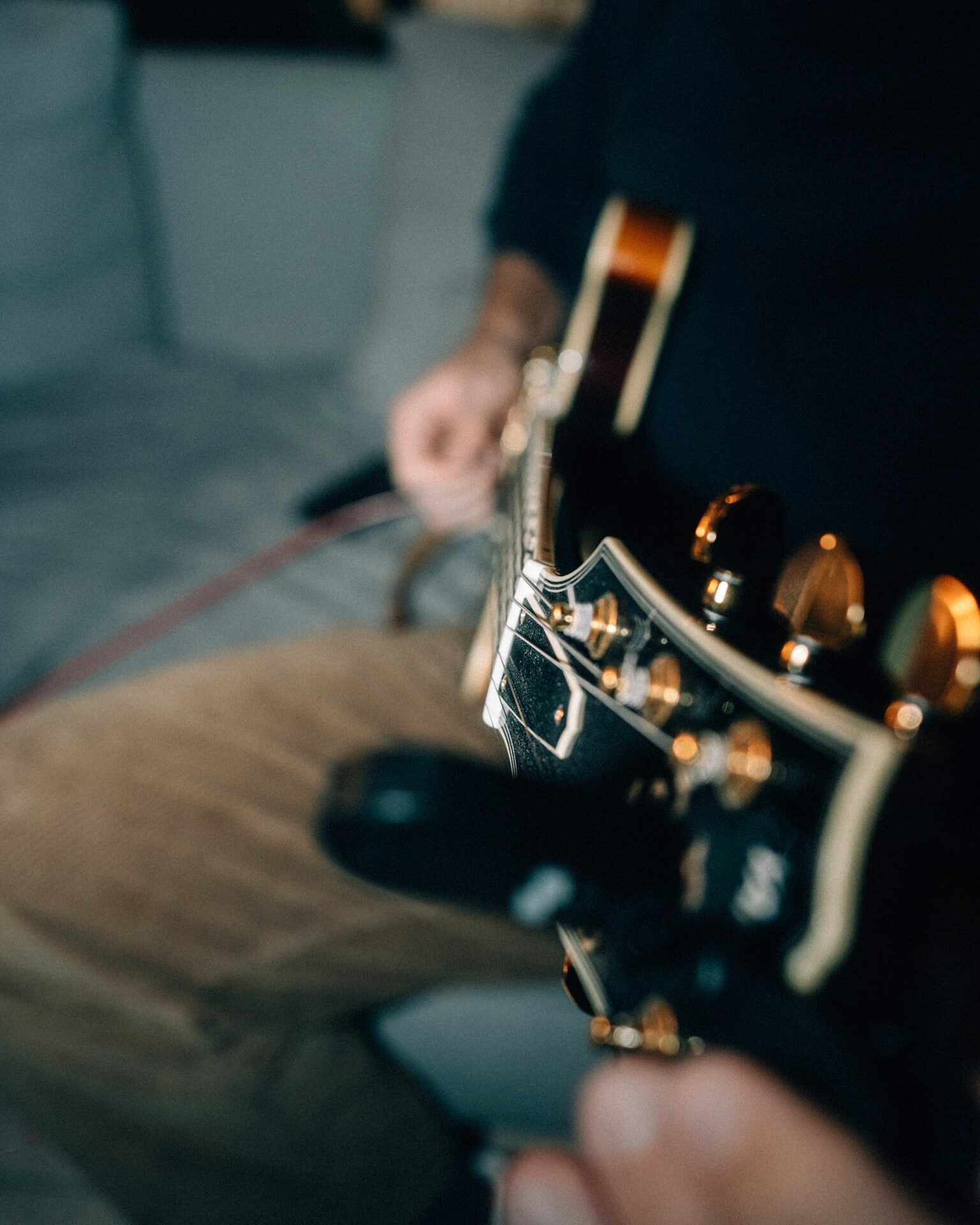 Musician playing a black electric guitar indoors