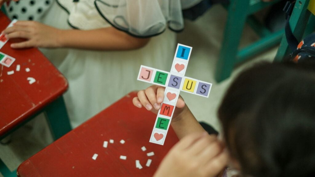 a young girl is holding a cross made of paper