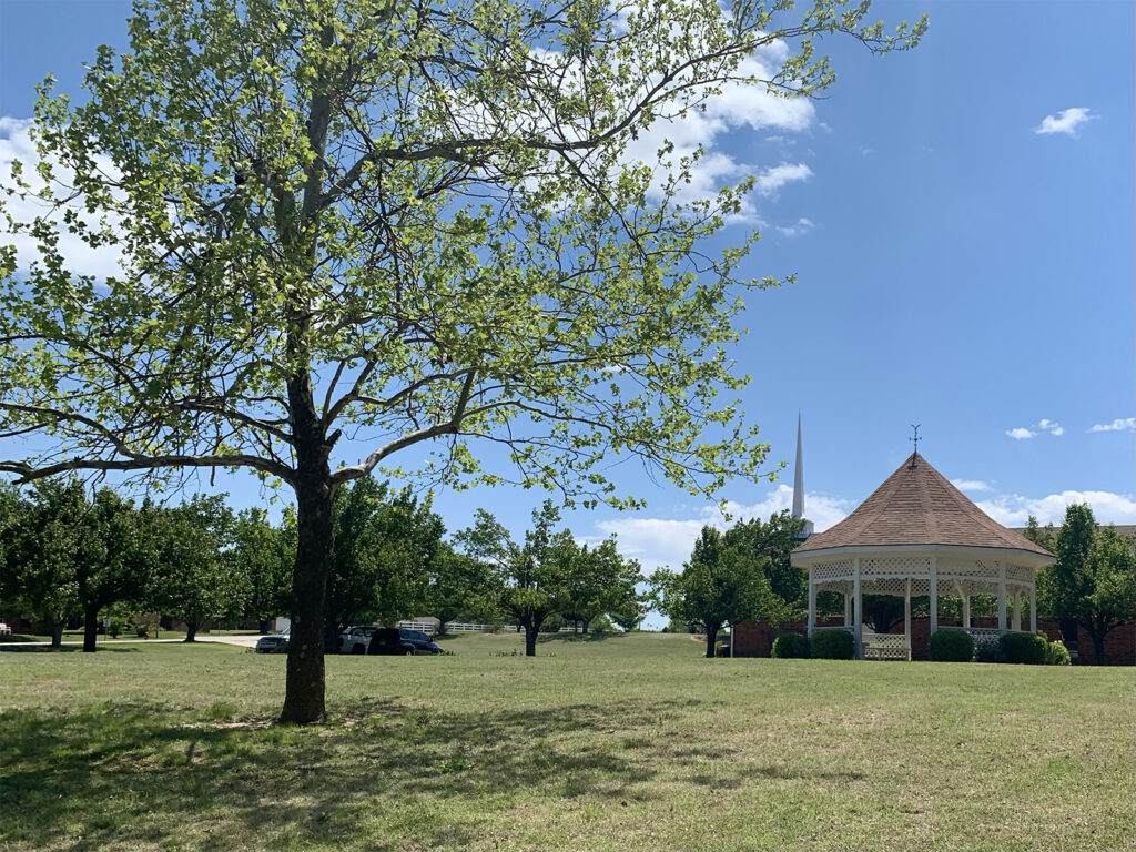 Green lawn and tree-filled grounds with gazebo and church at Summit Ridge Retirement Village