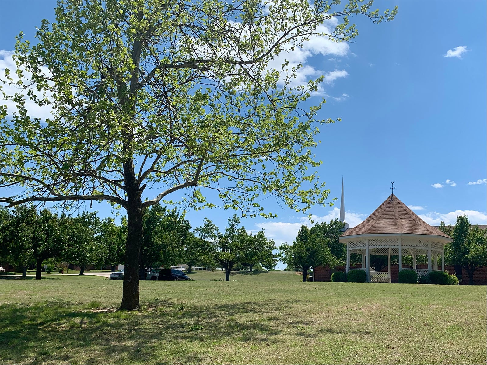Green lawn and tree-filled grounds with gazebo and church at Summit Ridge Retirement Village