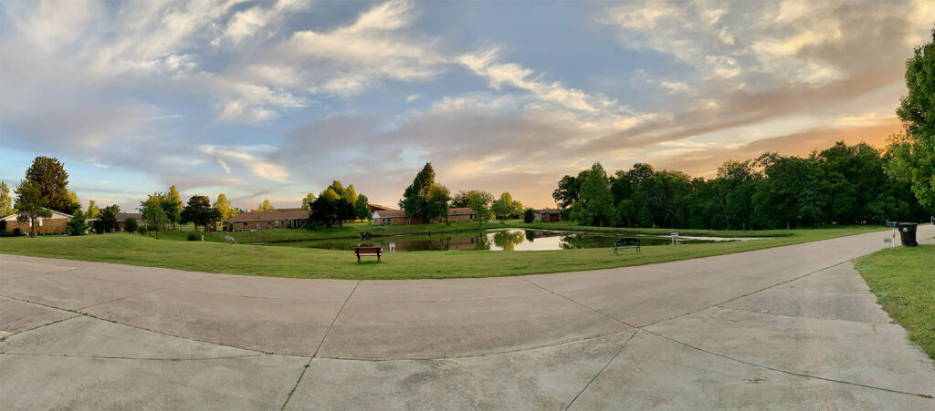 Pond with homes and green space at Summit Ridge Retirement Village during sunset