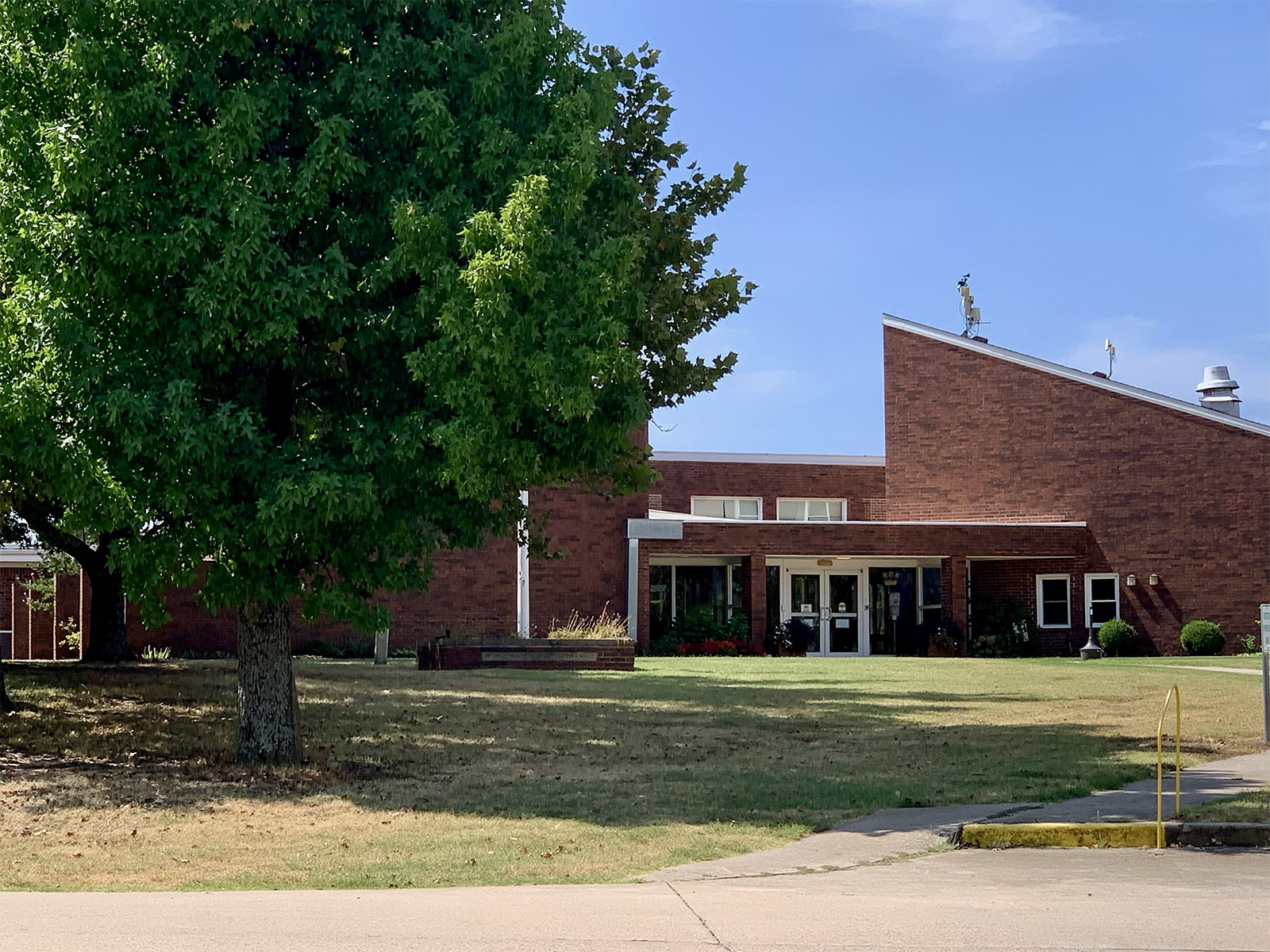 Entrance of The Wolfe Living Center building with landscaped lawn and shade tree