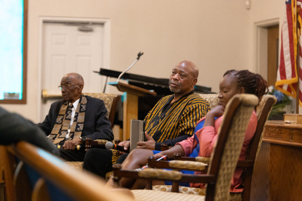 Image of a three individuals seated at the front of the church as part of a panel discussion.