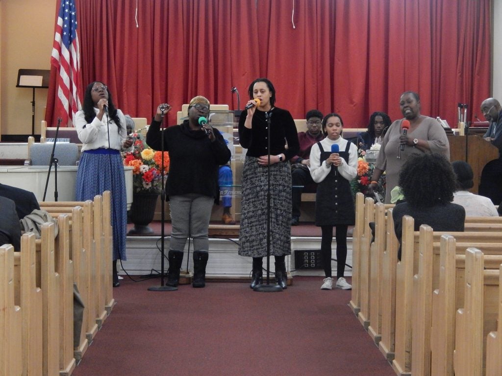 Church members singing together on the platform at the front of the sanctuary