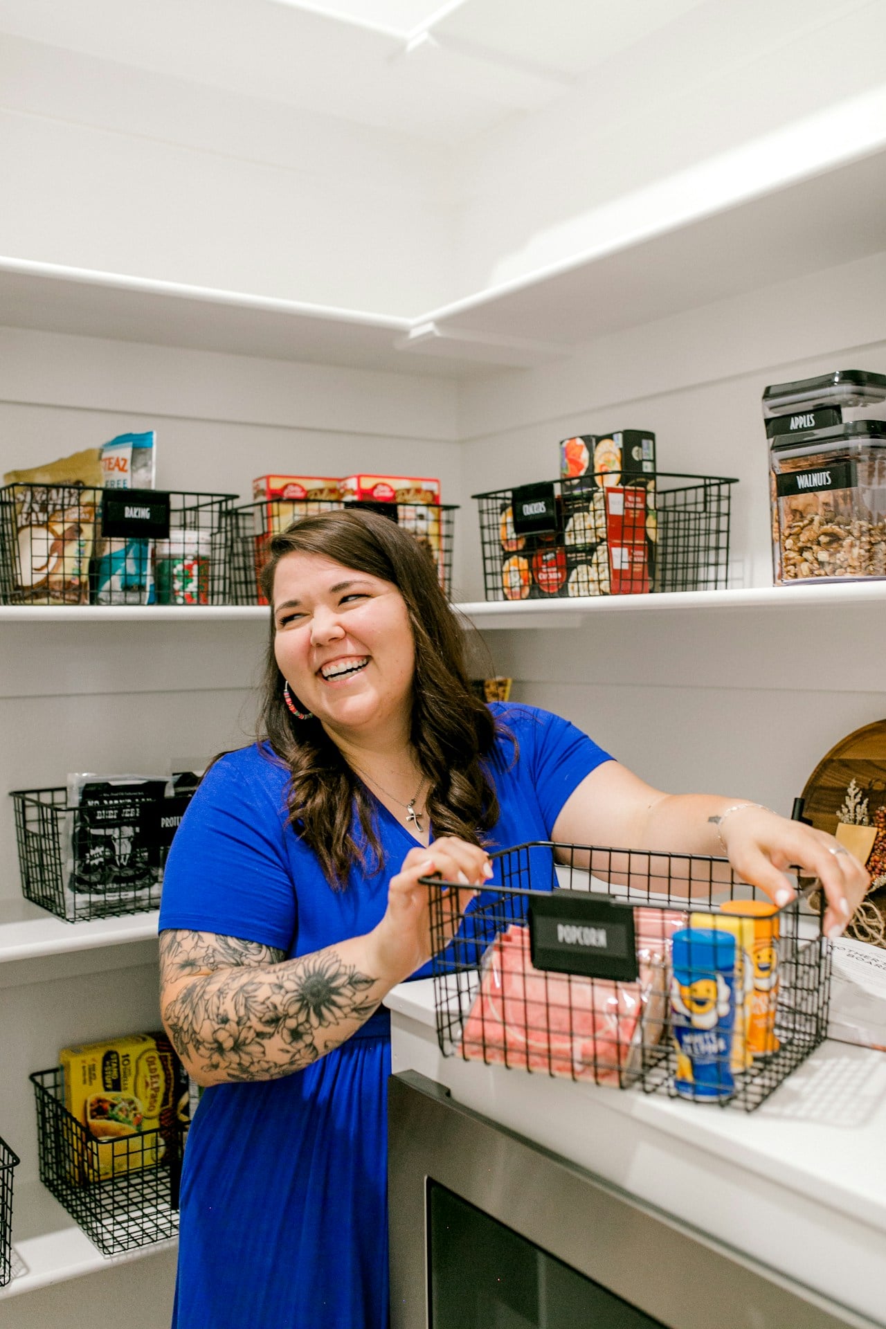 Woman organizing pantry with organized shelves and labeled shelves.
