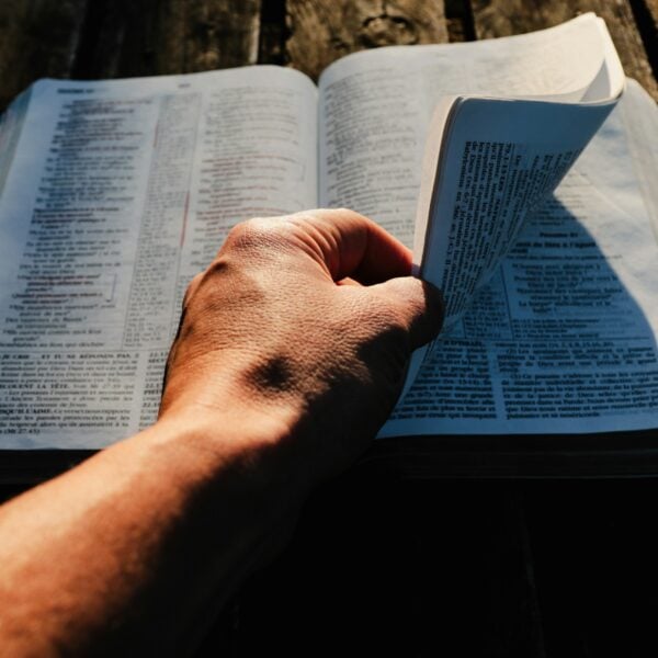 a person holding an open book on top of a wooden table