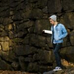 man reading book beside wall