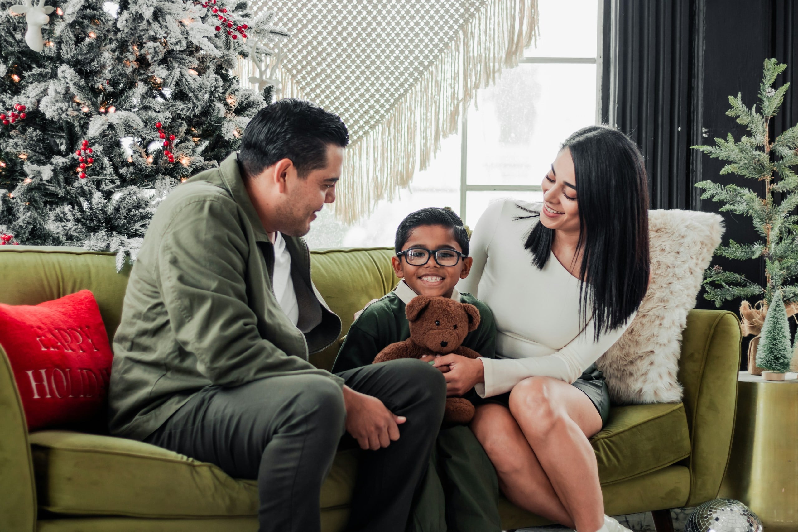 a family sitting on a couch in front of a christmas tree
