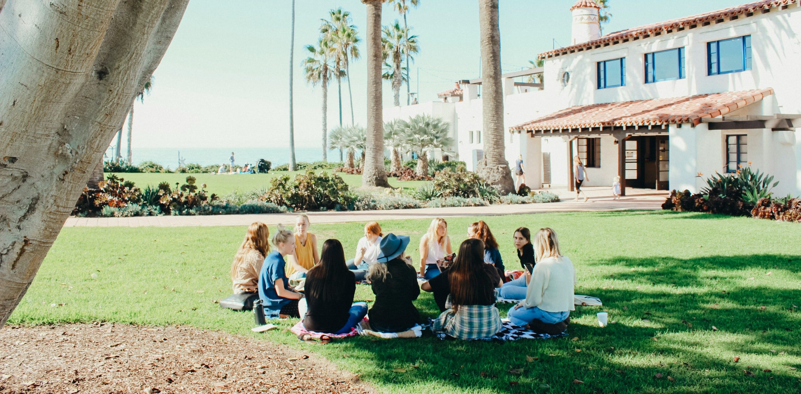 people sitting on ground while forming round during daytime