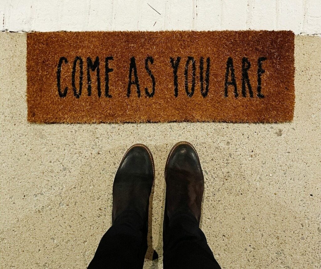 person standing on brown and black welcome printed floor mat