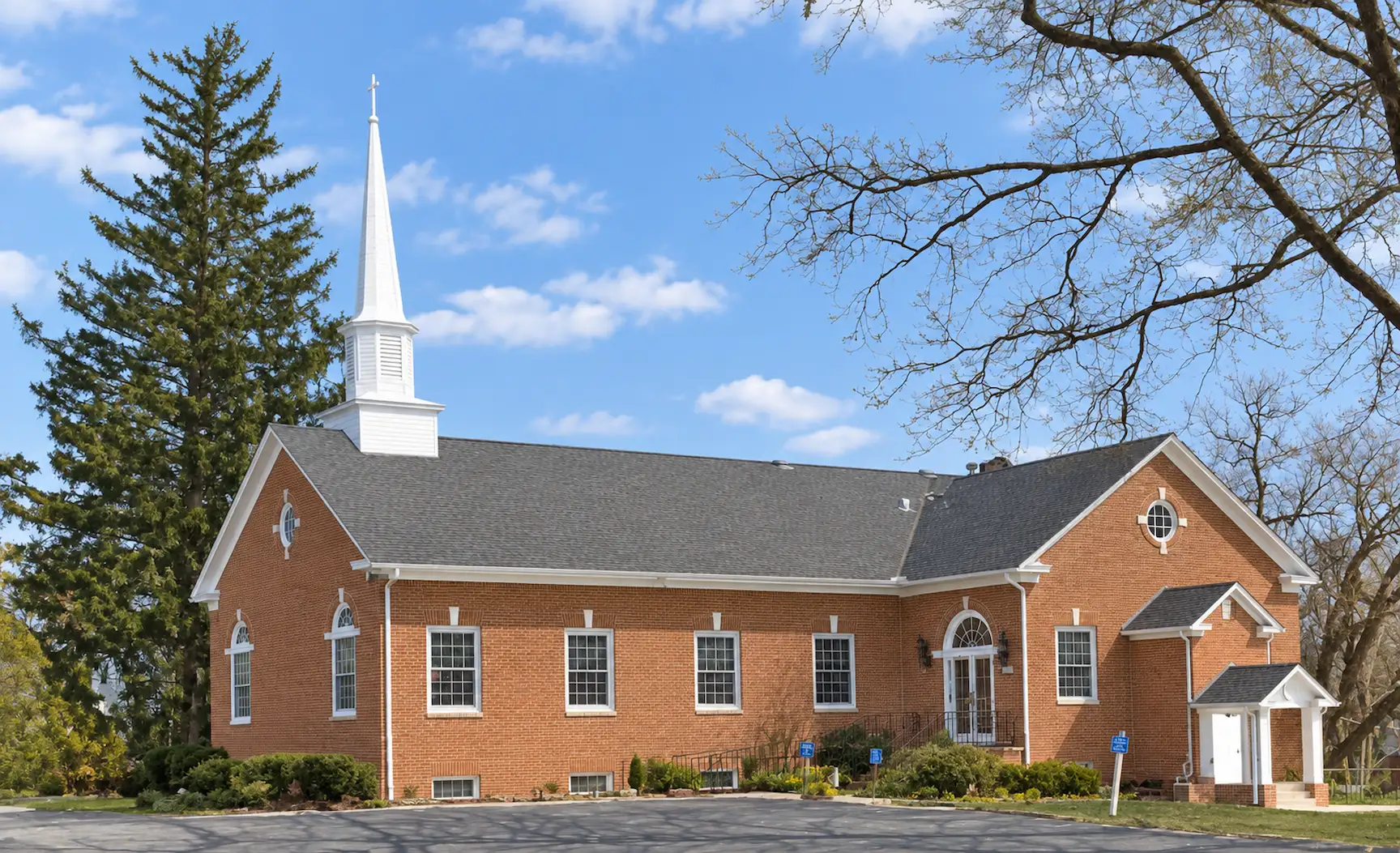 The Winchester Seventh-day Adventist Church building, a brick church with a white steeple, seen from the parking lot