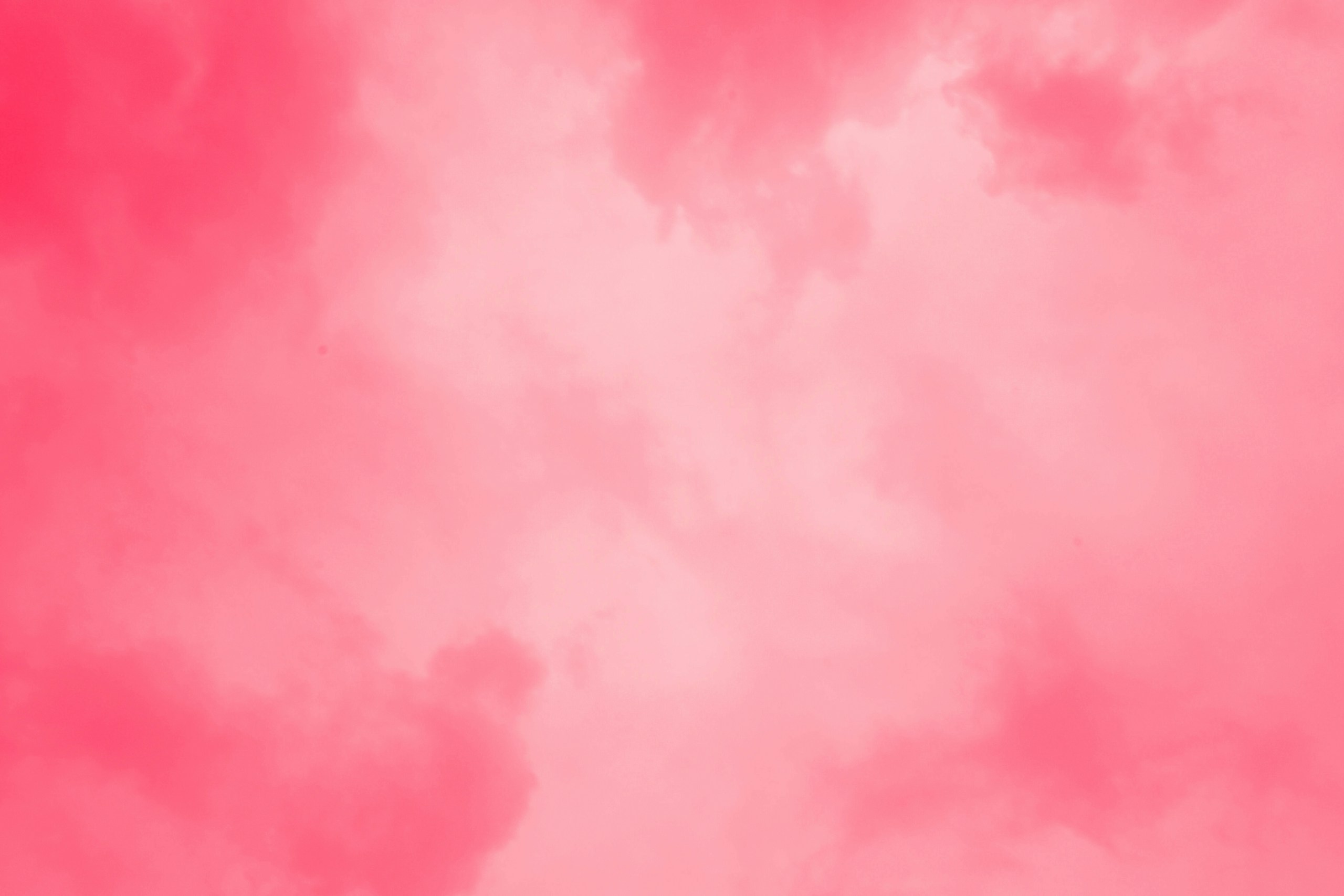a pink sky with a plane flying in the sky